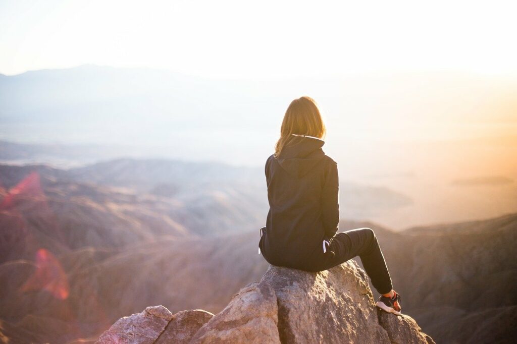 Frau sitzt auf Berg und denkt nach Der richtige BH zum Wandern Unsere Tipps